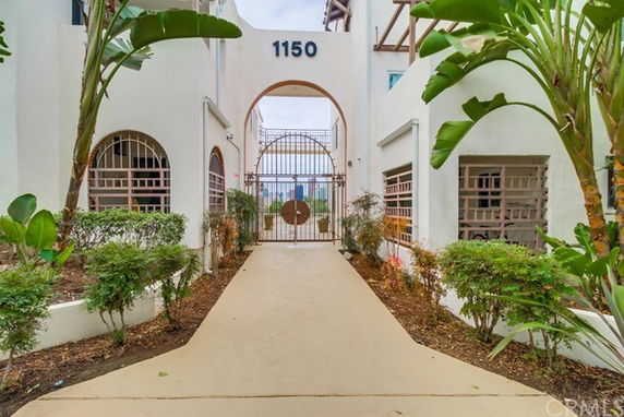 Entrance view of a multi-story building with arched gate and number 1150 displayed above.