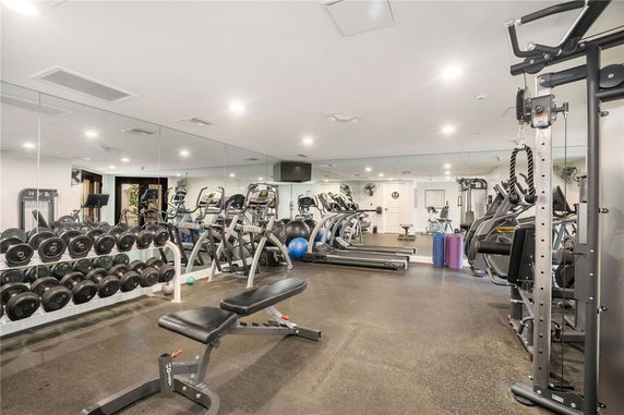 Indoor gym with exercise equipment and mirrors on the walls.