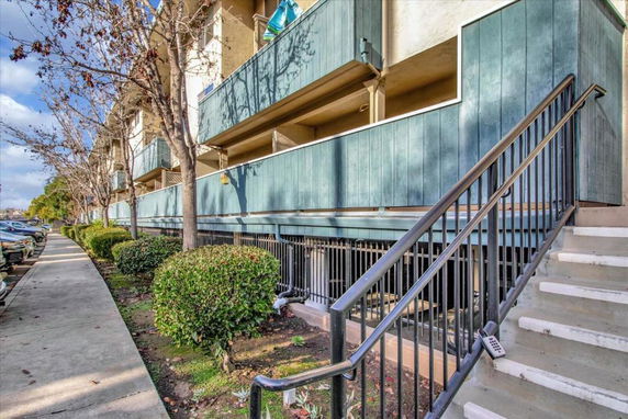 Front view of a multi-story building with balconies and exterior staircase.