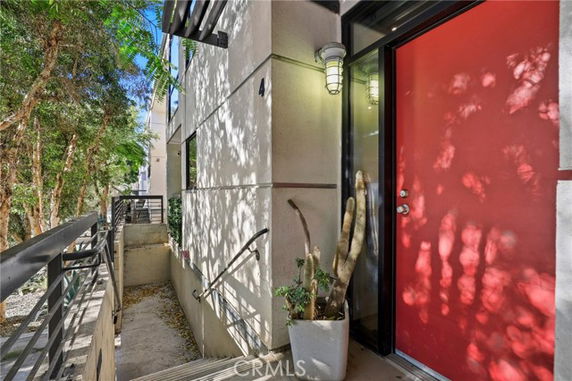 Front view of a modern building entrance with a red door and decorative plants.