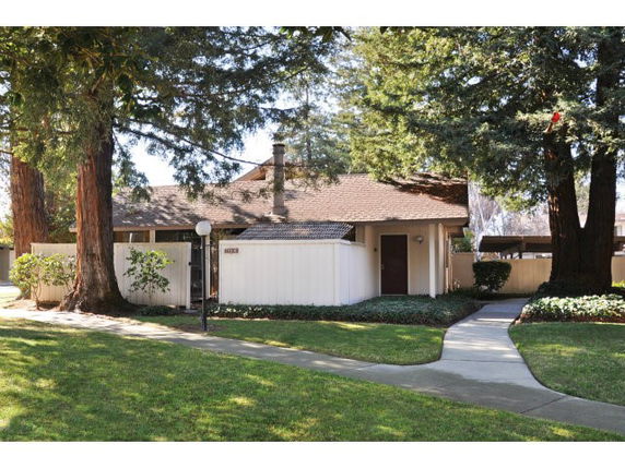 Front view of a single-story house with a sloped roof and wood paneling.