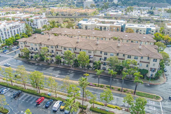 Aerial view of a multi-story residential building with a brown roof and trees around.