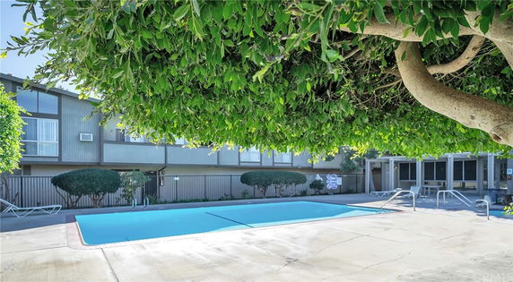 Outdoor swimming pool in front of a multi-story residential building.