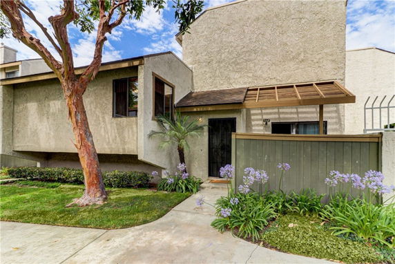 Front view of a house with a side entrance and a small fenced patio.