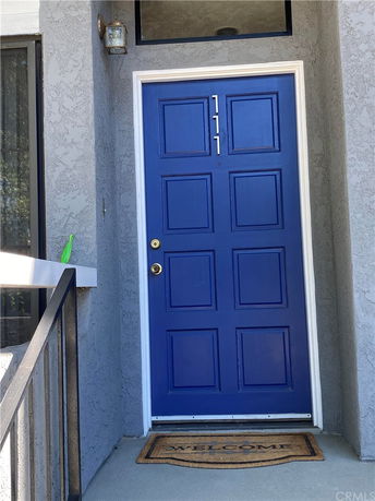 Front view of a house entrance with a blue door and welcome mat.