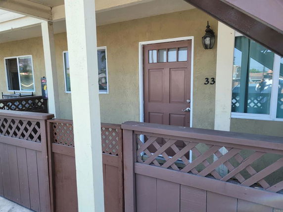 Front view of a building's entrance with a wooden door and adjacent windows.