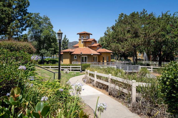 Front view of a multi-story house with red-tiled roof and surrounded by greenery.
