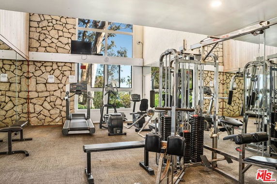 Interior view of a gym with various exercise equipment and stone walls.