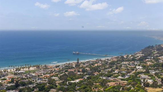 Panoramic view of a coastal area with ocean and beachfront houses.