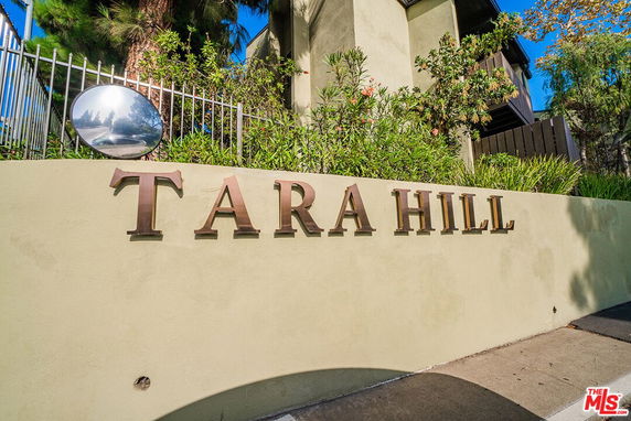 Entrance signage of a building labeled 'Tara Hill' with greenery and fencing.