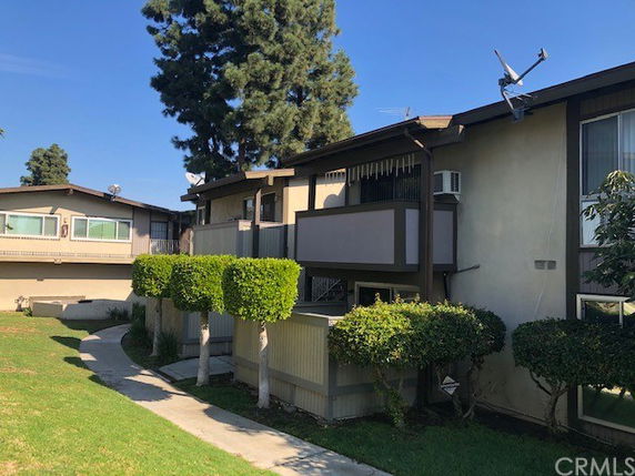 Front view of a two-story residential building with balconies and air conditioning units.