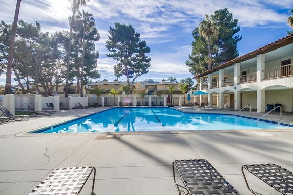 Outdoor swimming pool area with lounge chairs and surrounding trees.