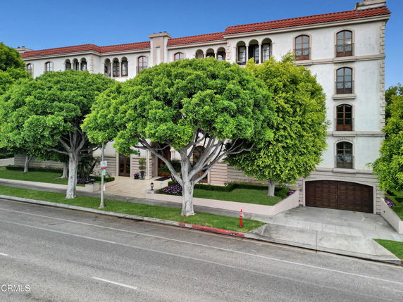Front view of a multi-story building with arched windows and a red-tiled roof.