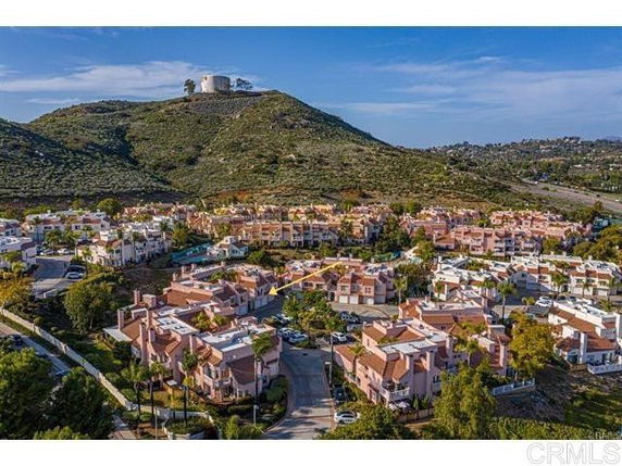 Aerial view of a residential area with multiple houses and a hill in the background.