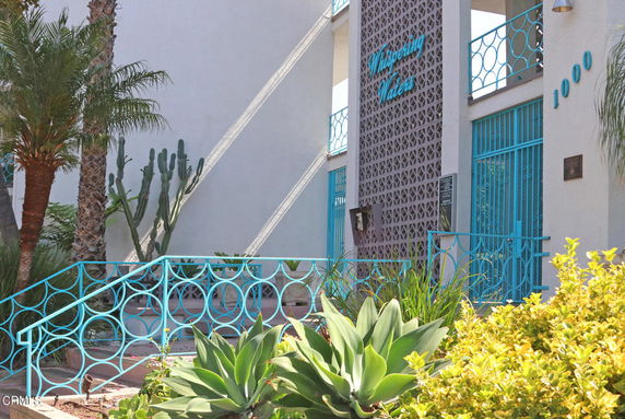 Front view of a residential building with turquoise railing and decorative facade.