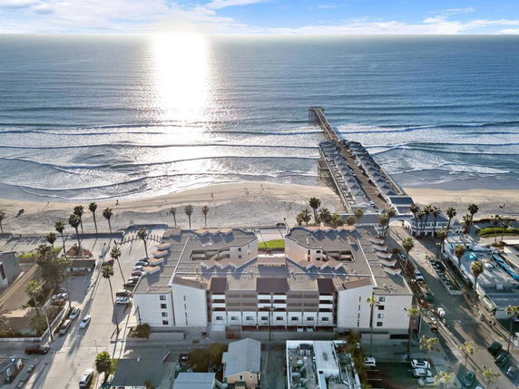 Aerial view of a beachfront area with buildings and a pier extending into the ocean.