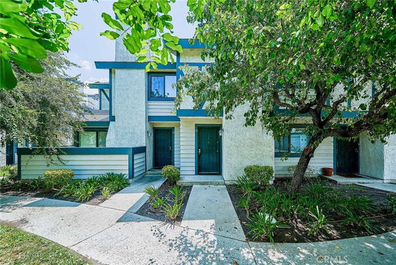 Front view of a two-story house with a contemporary design, including blue trim and a small front garden area.