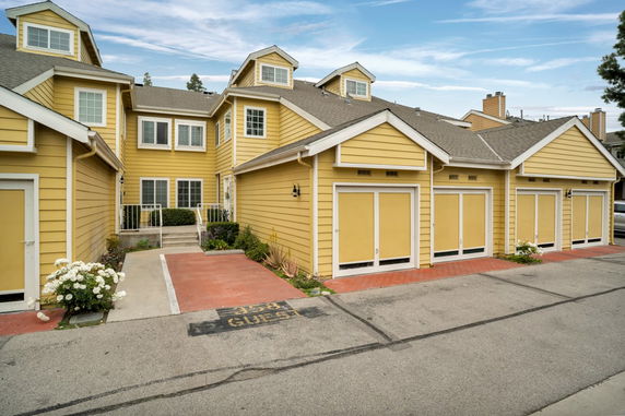 Front view of a two-story building with yellow exterior and multiple garage doors.