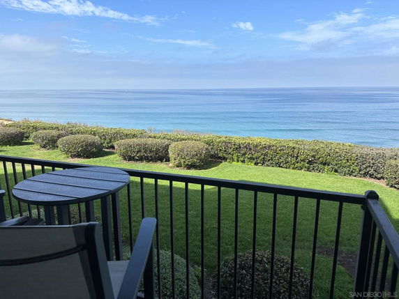 Panoramic view of the ocean seen from a balcony with a table and chairs.