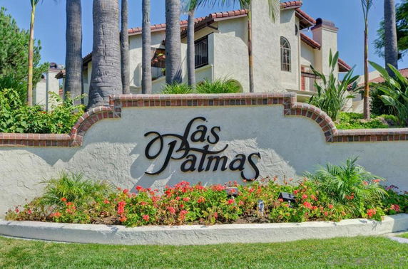 Front view of a house with a sign reading 'Las Palmas', featuring Mediterranean-style architecture with a tile roof.