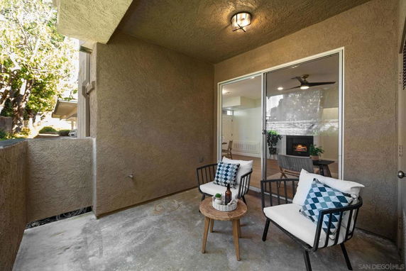 Covered outdoor seating area with chairs and a small table.