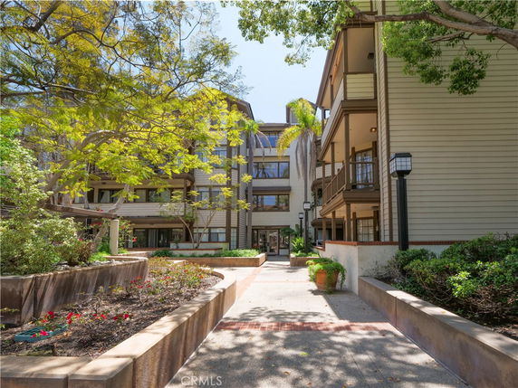 Front view of a multi-story residential building with balconies and landscaped entrance.