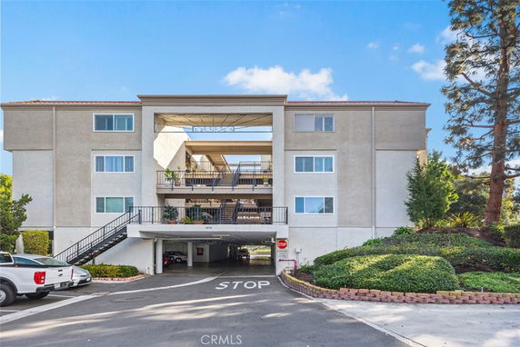 Front view of a multi-story apartment building with a parking area underneath.