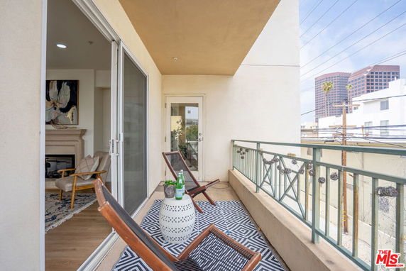 Balcony with chairs and decorative elements overlooking city buildings.