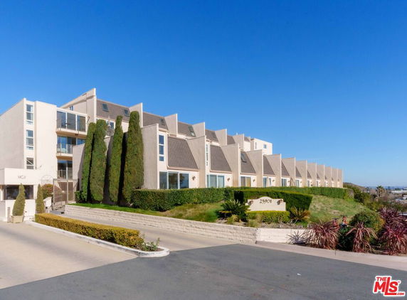 Front view of a modern multi-story residential building with unique roof design.