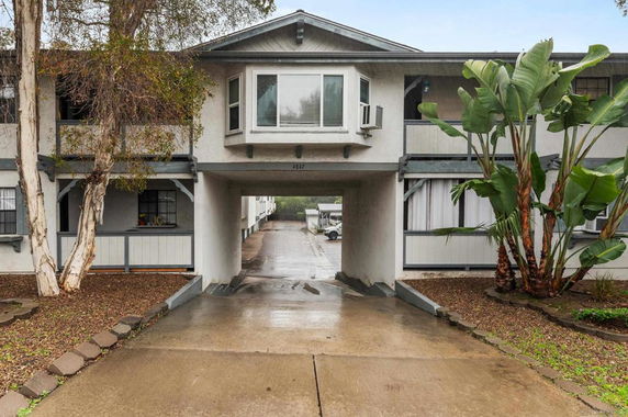 Front view of a two-story apartment building with a central car passageway.