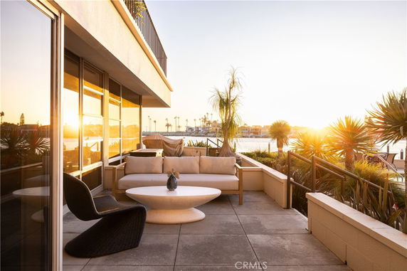 Terrace with modern seating overlooking water at sunset.