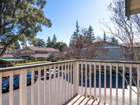 View from a balcony showing nearby houses and trees.