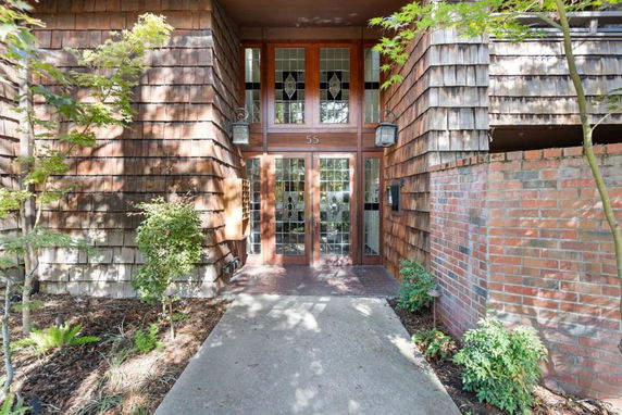 Front view of a house with wood shingle siding and glass doors.