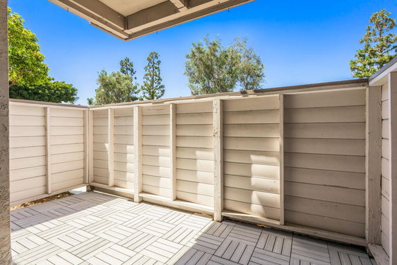 Enclosed outdoor area with wooden panel fencing and tiled flooring.