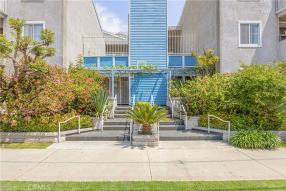 Front view of a building with blue accents and lush greenery.