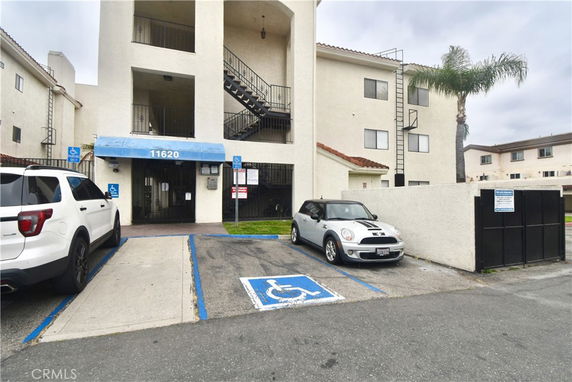 Front view of a multi-story apartment building with parking spaces.