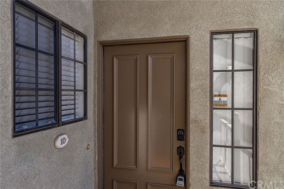 Front view of a building entrance with a brown door and adjacent windows.