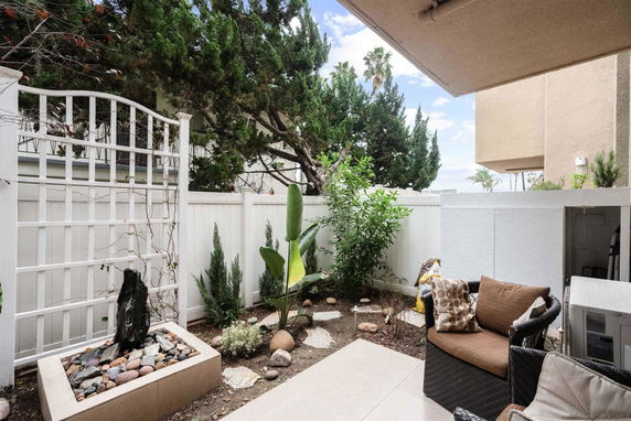 Outdoor area with seating and garden enclosed by a white fence.