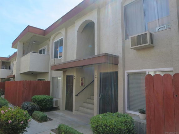 Front view of a two-story residential building with balconies and air conditioning units.