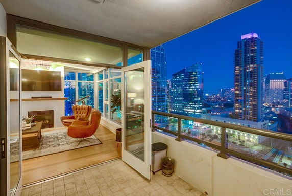 Panoramic view from a balcony overlooking a city skyline with illuminated skyscrapers at night.