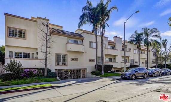 Front view of a multi-story residential building with balconies and a driveway.