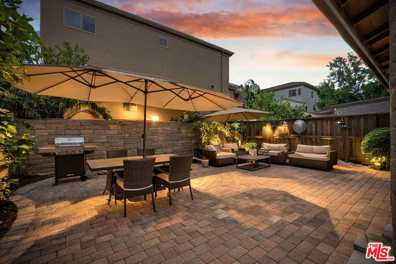 Outdoor patio area with seating, umbrellas, and a barbecue grill.