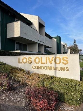 Front view of a condominium building with a sign reading 'Los Olivos Condominiums'.
