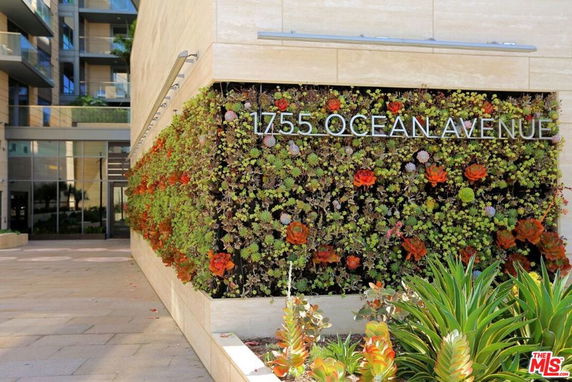 Front view of a building entrance with a vertical garden wall displaying the address.