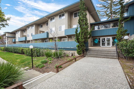 Front view of a multi-story residential building with balconies and a central entrance.
