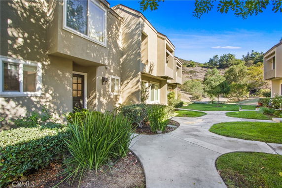 Front view of a two-story house with beige exterior and large windows.