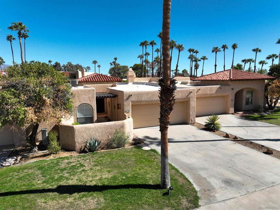 Front view of a single-story house with a stucco exterior and three-car garage.