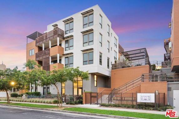 Front view of a modern multi-story building with balconies and outdoor stairs.