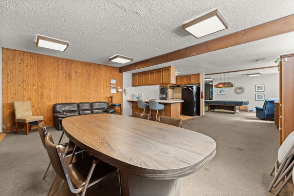 Interior view of a recreational common area with seating, a table, and a pool table.