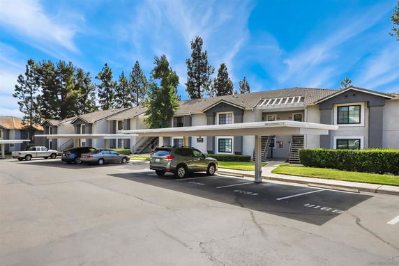 Outdoor parking area in front of a residential building with covered parking spaces.